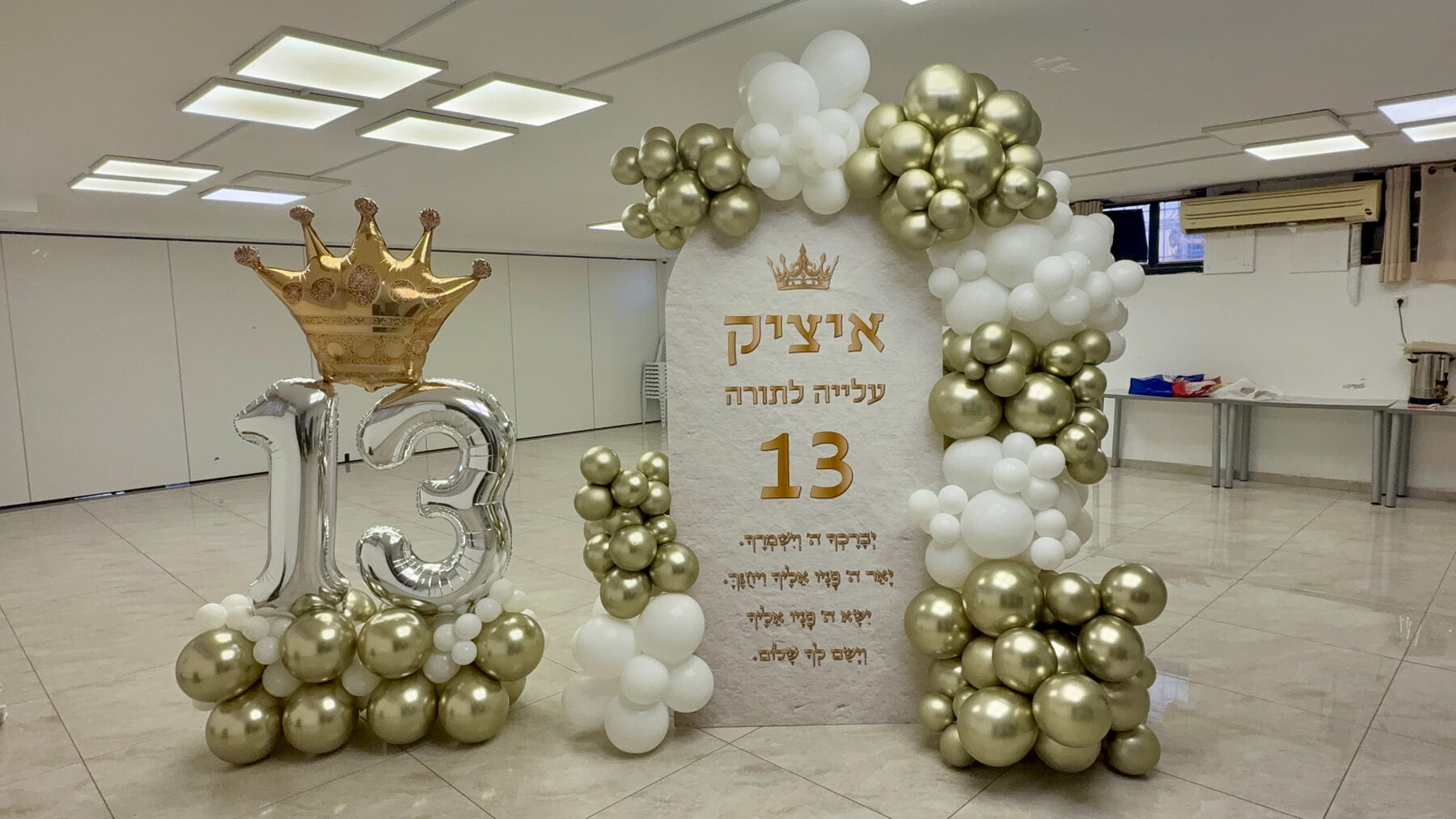 עיצוב בר מצווה בגווני לבן וזהב עם קיר ממותג